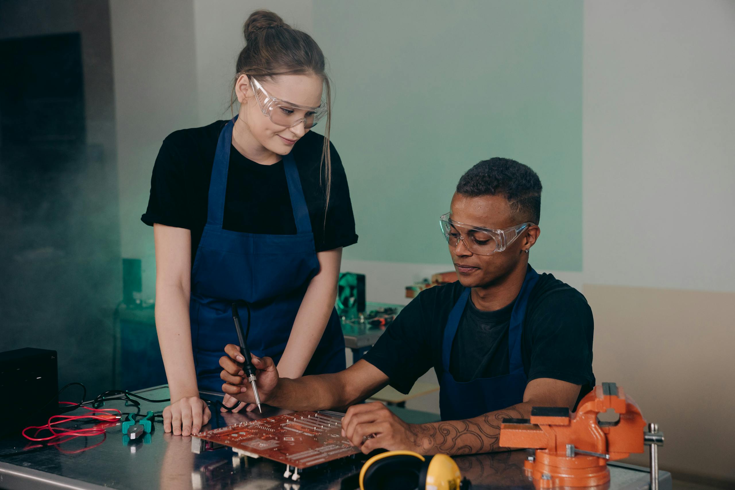 Two engineers collaborating on circuit board assembly in a technical workspace.