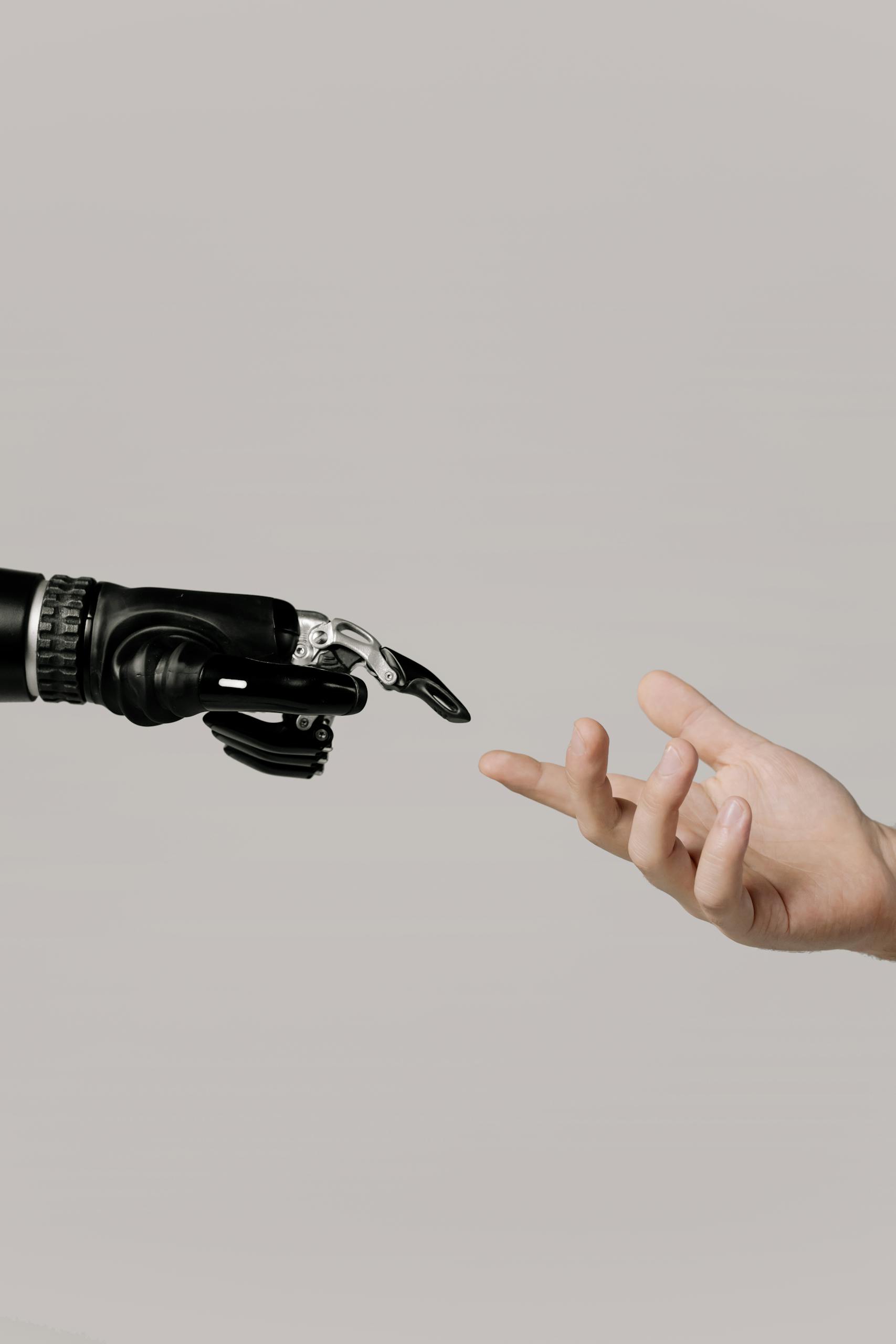Manufacturing 14 A human hand reaching to touch a bionic prosthetic hand on a white background.