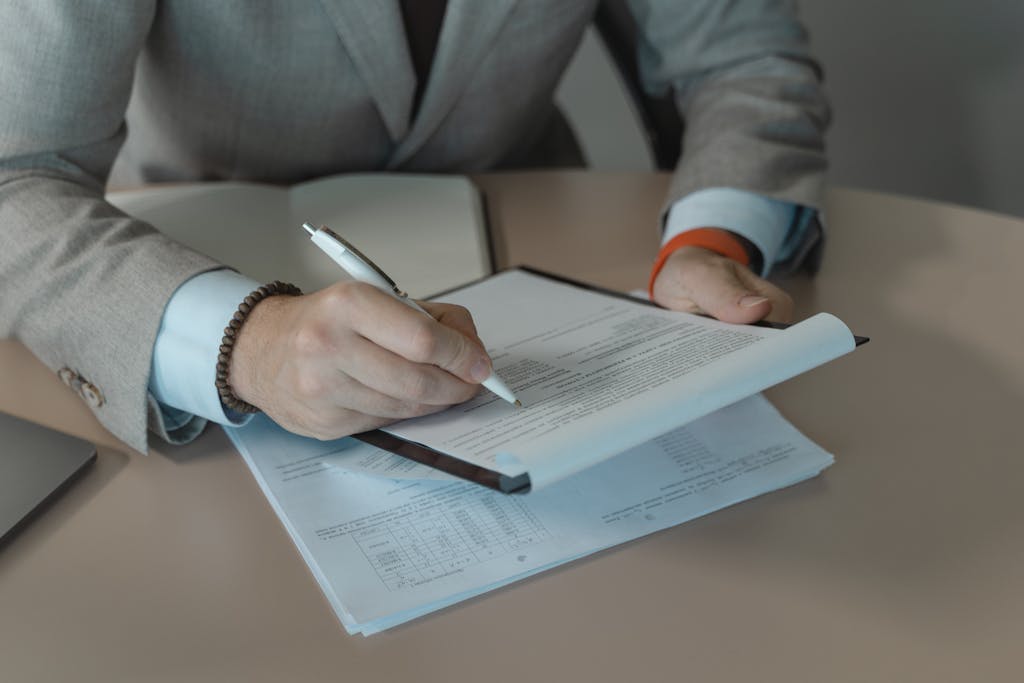 Manufacturing 12 Close-up of business person signing documents at a desk with a pen.