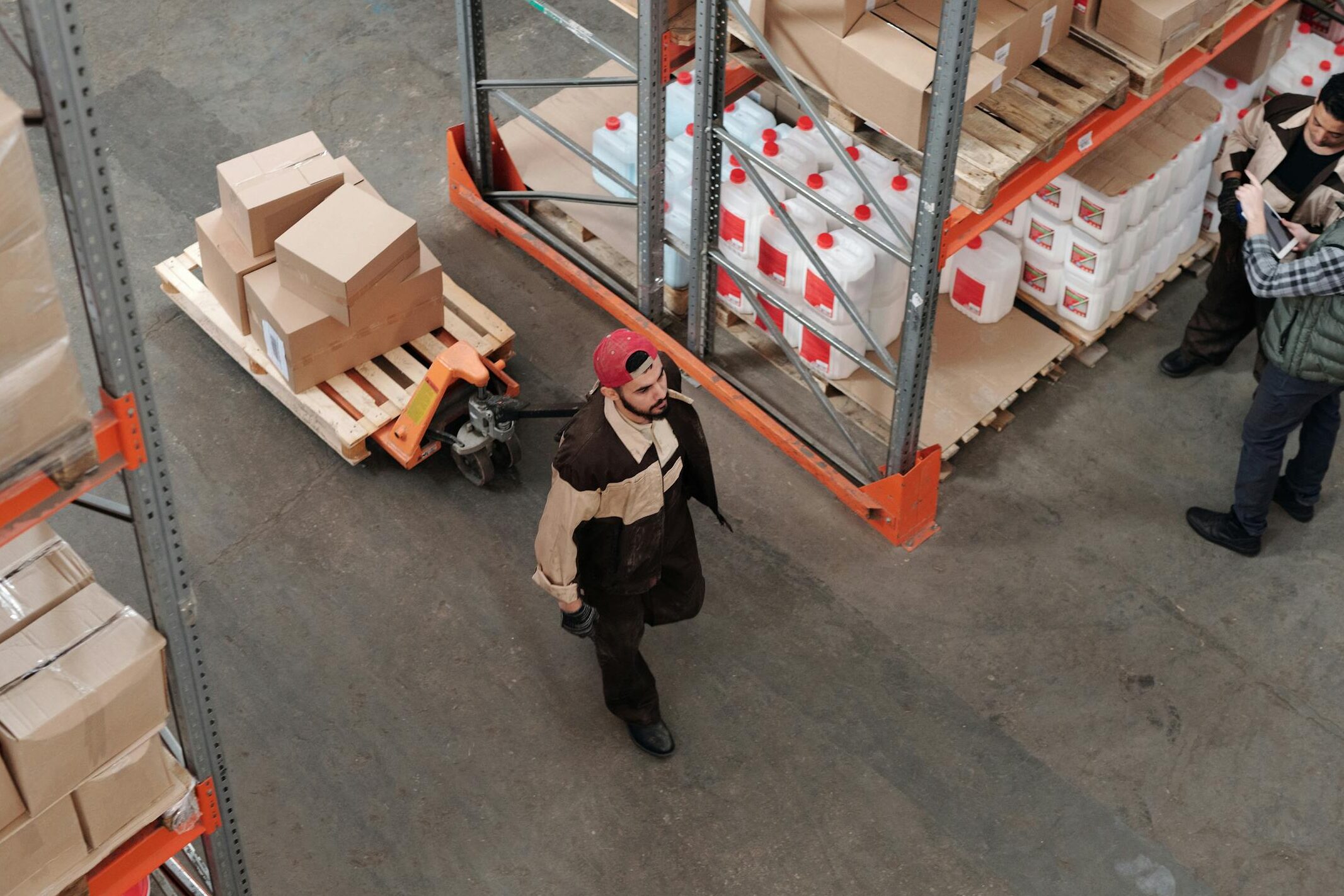 Team working in an industrial warehouse discussing and organizing inventory with pallets.