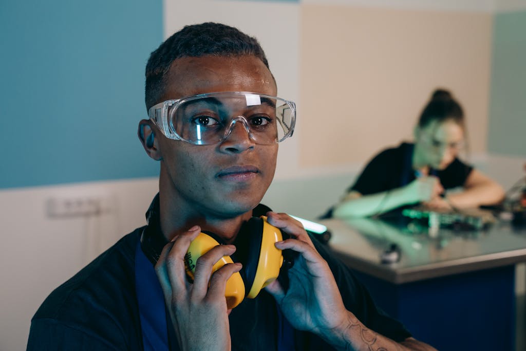 Young engineer wearing protective gear in a workshop setting, ensuring safety standards.