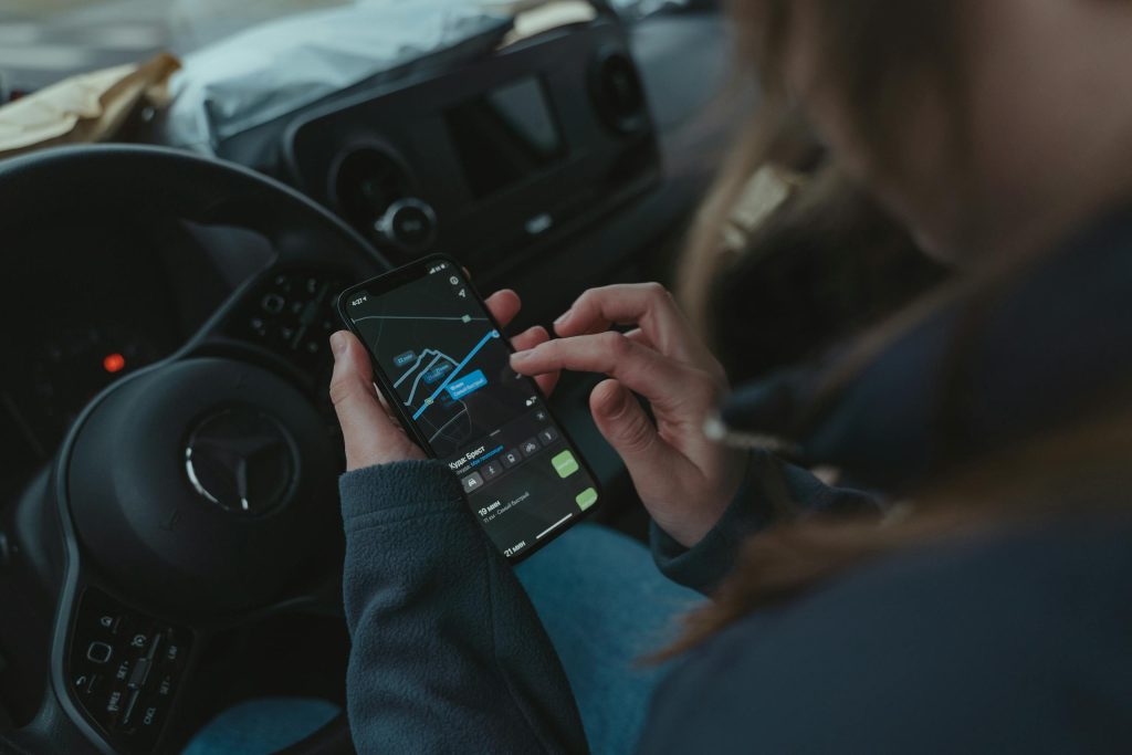 Person using GPS navigation app on smartphone inside car for directions.