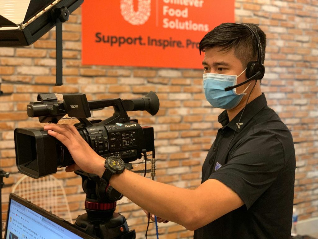 Professional videographer with headset operating camera in an indoor studio setting.